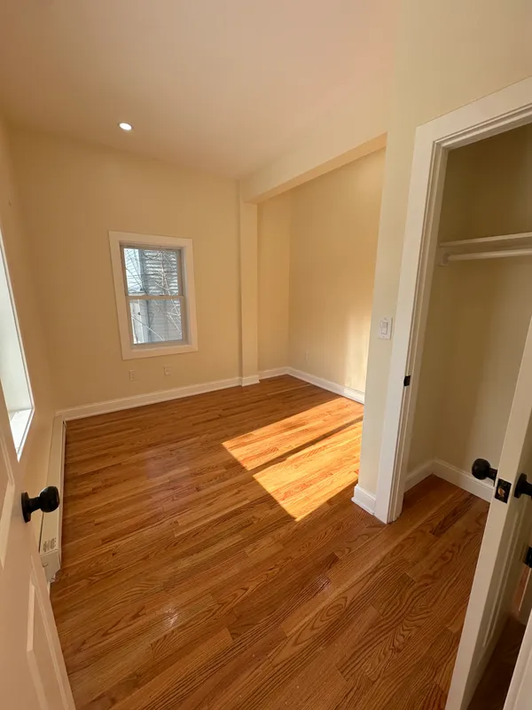 Empty room with hardwood floors and white walls during renovation.