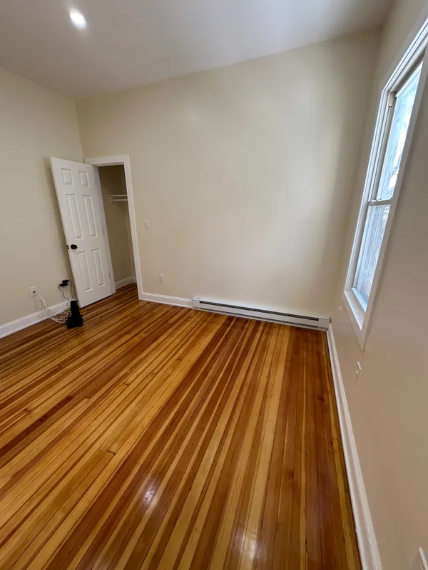 Empty room with polished hardwood floors and beige walls.
