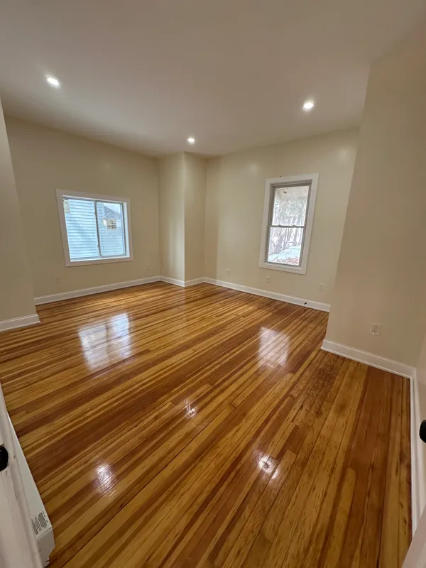 Empty room with polished hardwood floors and beige walls.