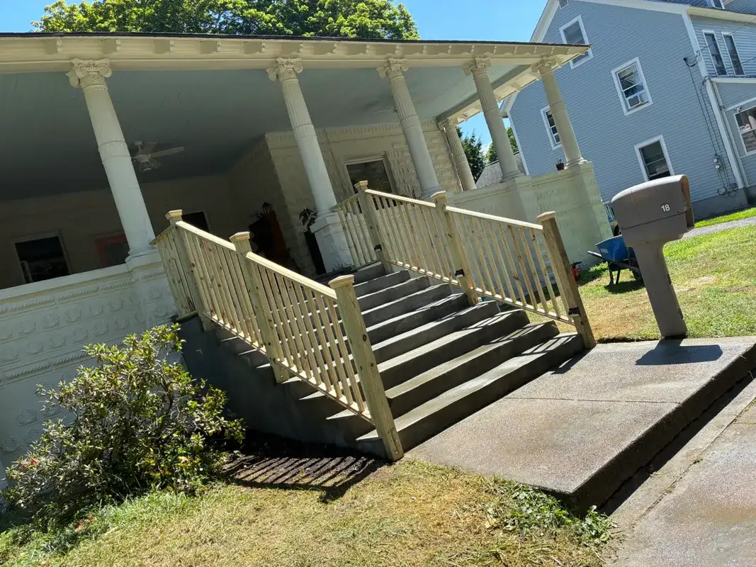 Front porch of a white house with wooden railings and steps.