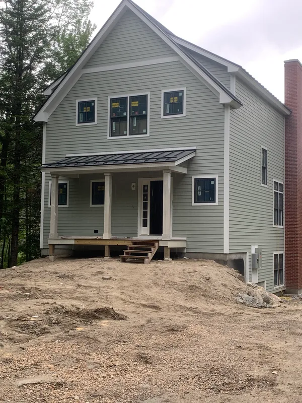 New gray siding house with a porch and wooden deck under construction.