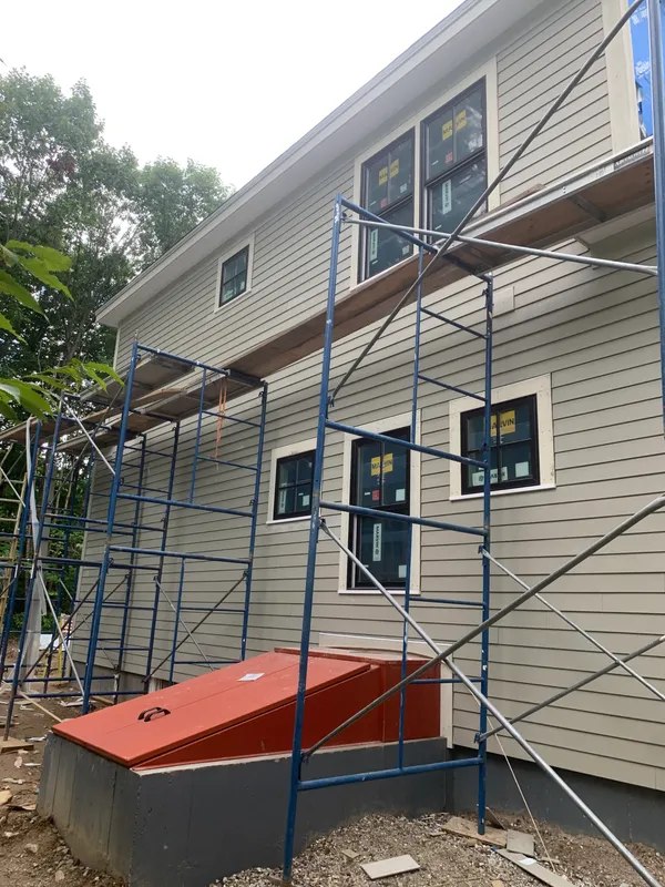 New gray siding house with a white garage and stone foundation.