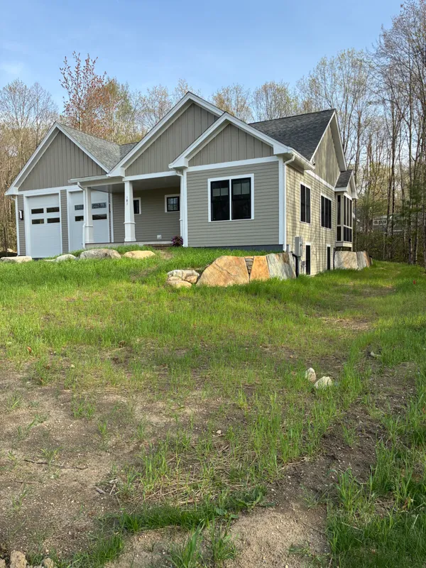 New gray siding house with a white garage and stone foundation.