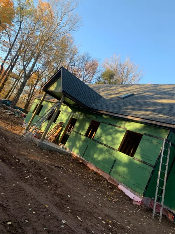 House under construction with green house wrap and new roofing.