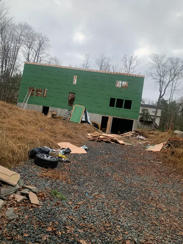 House under construction with green house wrap and wooden framing.