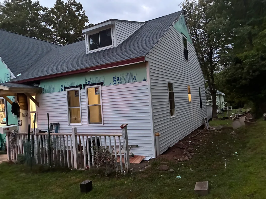 House under construction with new siding and roof installation.