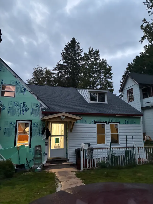 House under construction with new siding and roofing by JMC Construction.