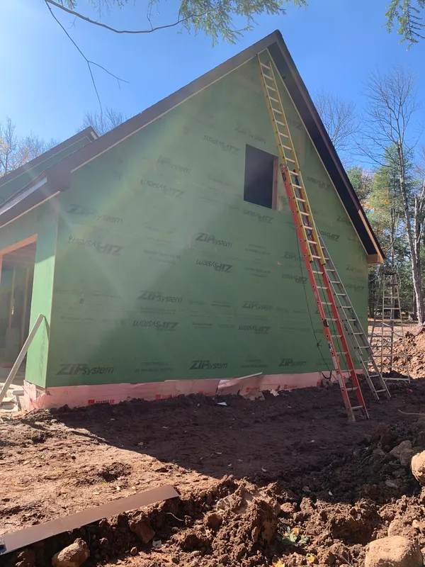 House under construction with green Zip System sheathing and a ladder.