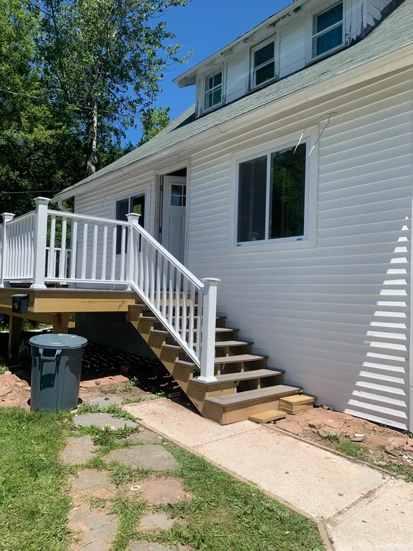 New white vinyl siding and wooden deck stairs on a house.