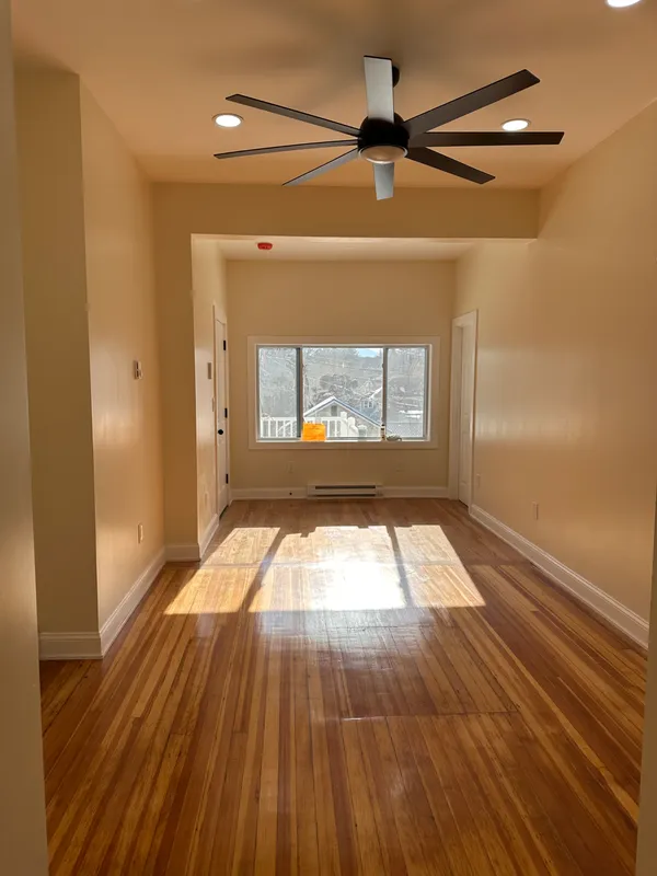 Interior view of a hallway with hardwood floors and a ceiling fan.