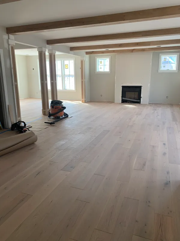 Interior of a house under construction with wood floors and beams.
