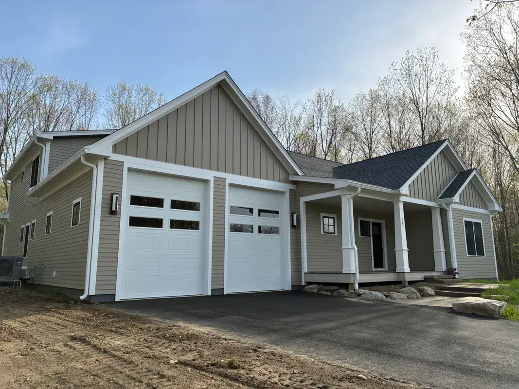 Modern tan house with white trim and two garage doors.