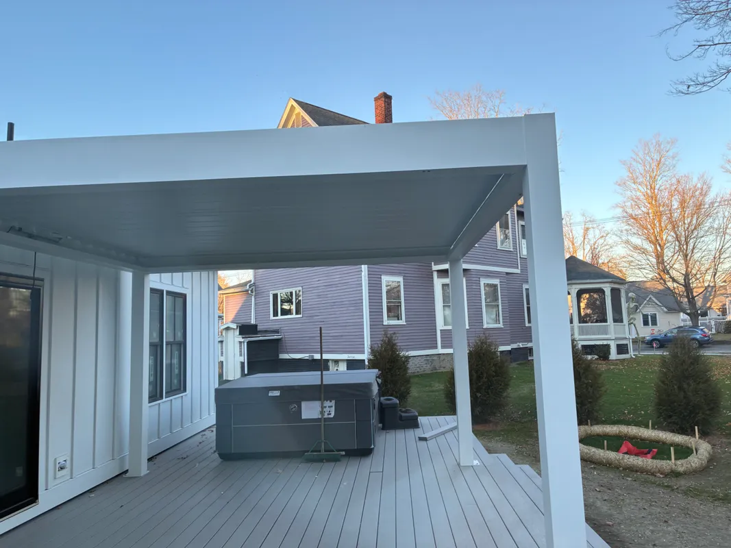 Modern white covered deck with a hot tub and backyard view.