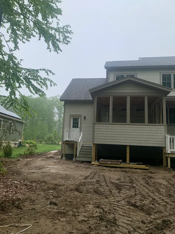 New house under construction with siding and a large porch.