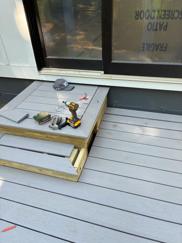 Power tools and materials on a new gray composite deck construction site.
