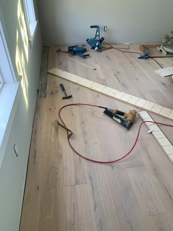 Power tools and wood planks on a new hardwood floor installation site.