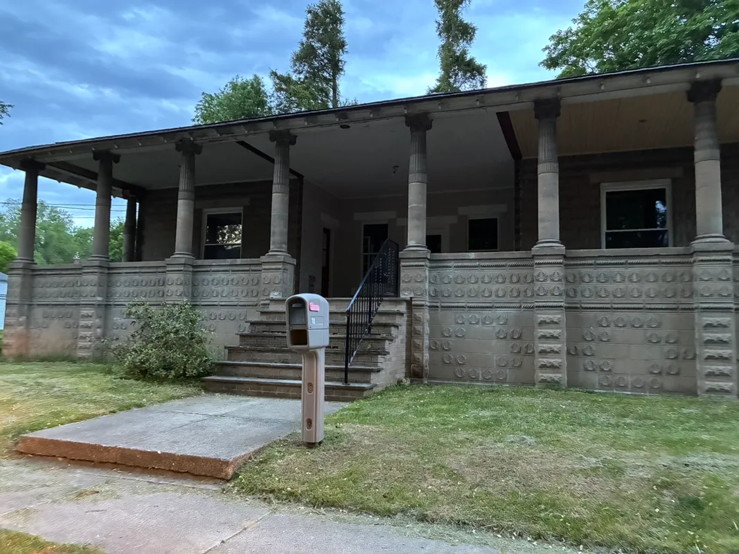 Stone porch of a house with columns and a mailbox.
