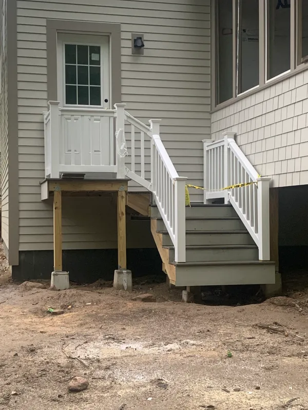 New white deck and stairs with wooden supports under construction.