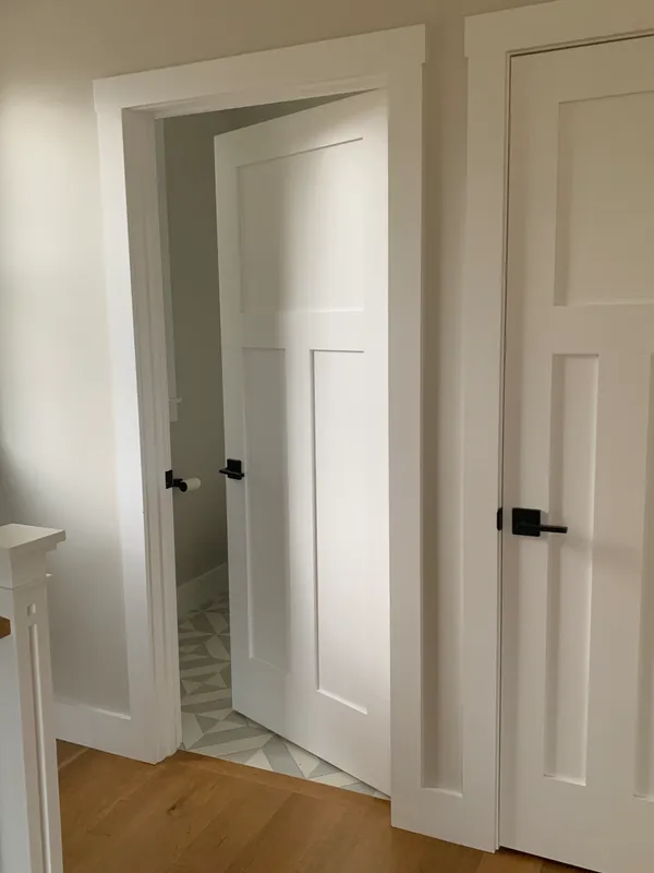 White interior doors with black handles and wood flooring in a home.