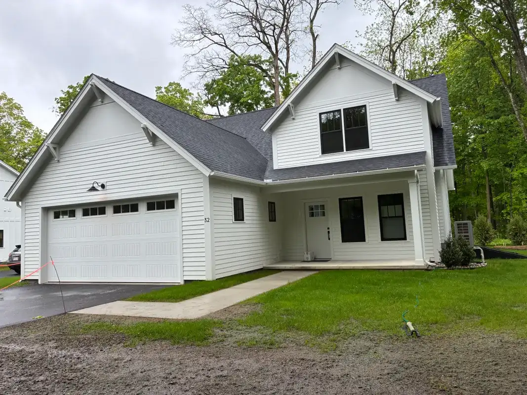 White siding house with a black shingled roof and two-car garage.