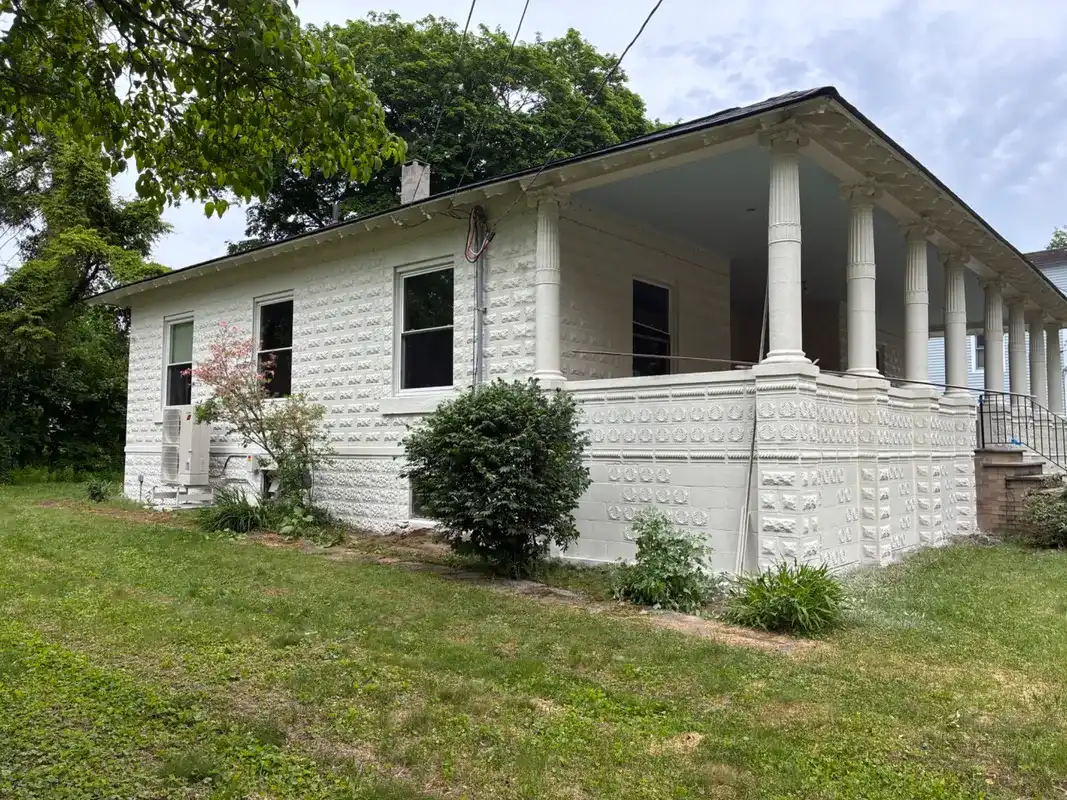 White stone house with a large covered porch and pillars.