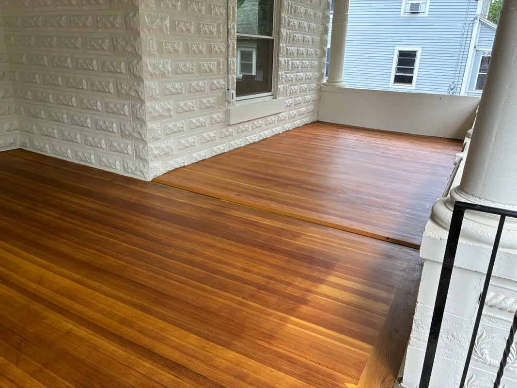New wood deck with white stone siding and a porch railing.