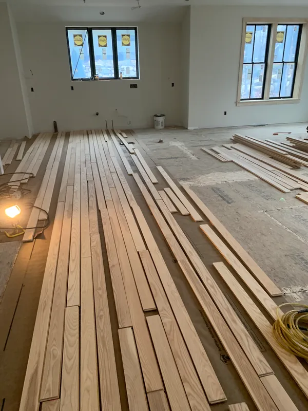 Wooden floor planks laid out in a room under construction.