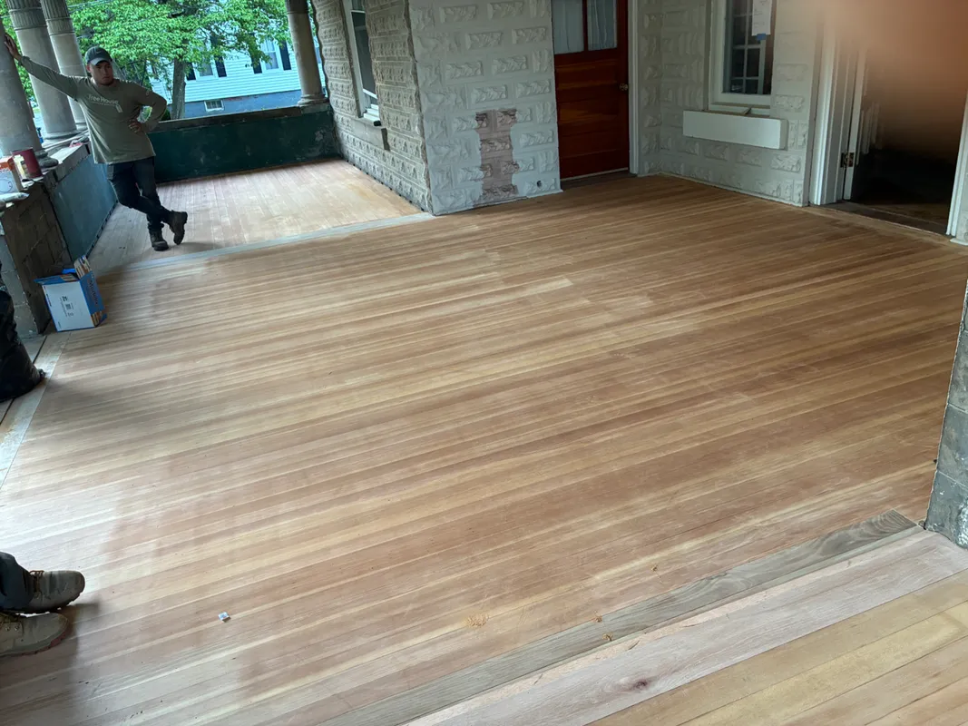 Workers installing new light wood flooring in a residential home interior.